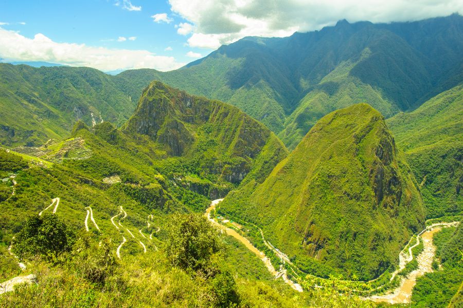 Vue panoramique sur les montagnes verdoyantes et les routes sinueuses des Andes au Pérou, destination incontournable pour faire en Amérique du Sud un voyage inoubliable.