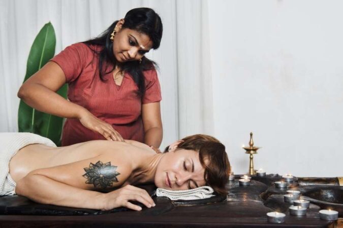 Une praticienne réalise un massage ayurvédique relaxant sur une femme allongée dans un salon de bien-être.